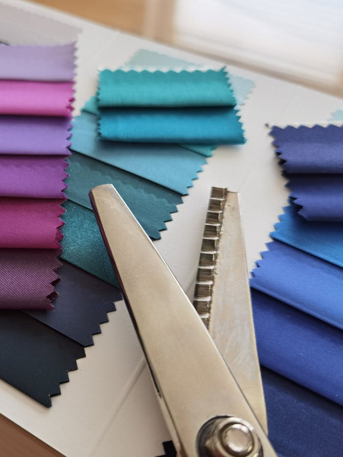 services-04 A variety of colorful fabric swatches displayed with pinking shears, perfect for design projects.