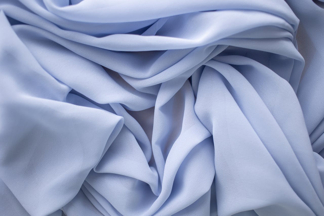 team-04 Close-up of light blue fabric with elegant folds and delicate texture, perfect for backgrounds.