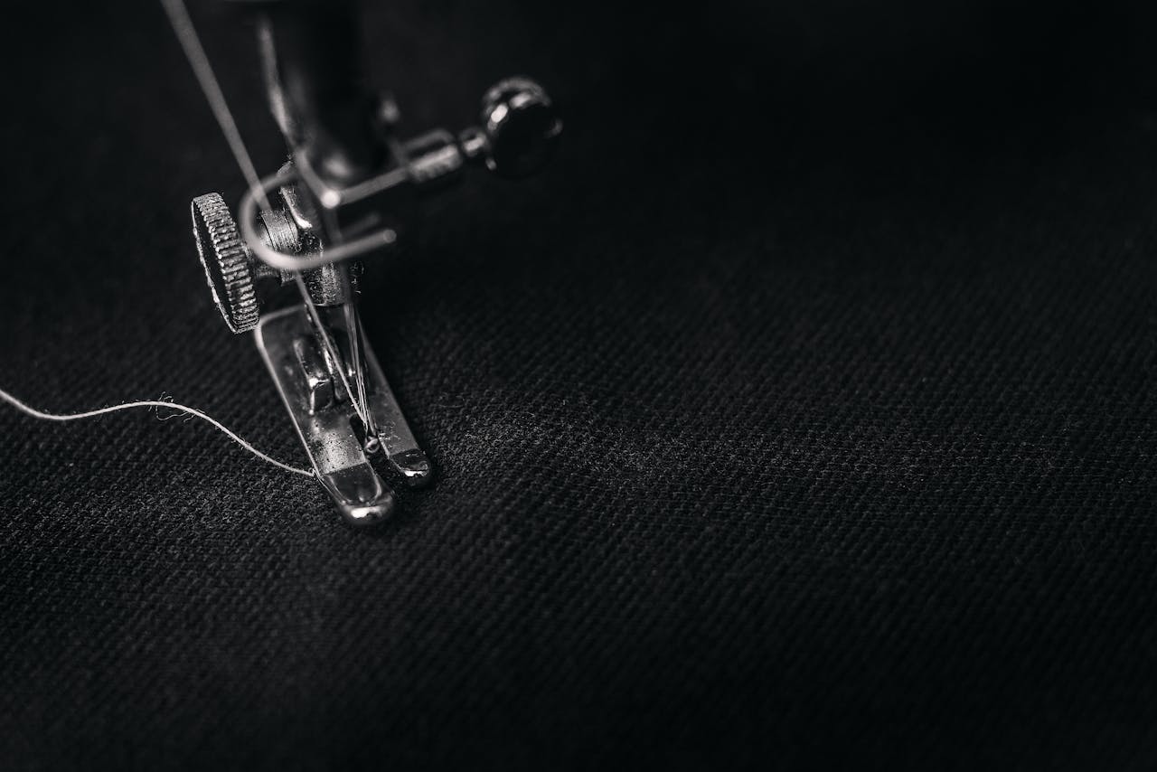 team-01 Detailed view of a sewing machine needle stitching fabric, highlighting sewing process and textile technology.