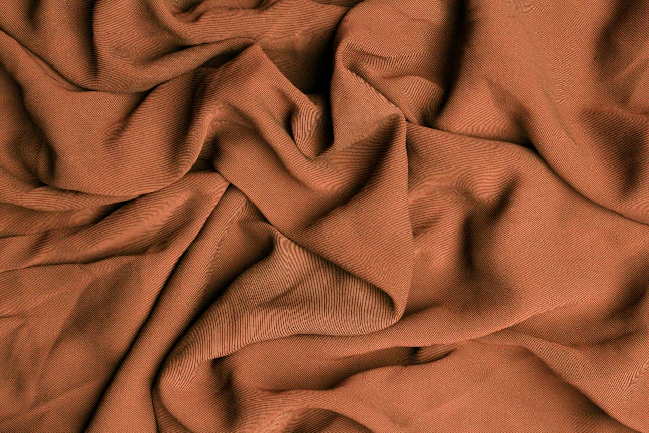services-02 Close-up of brown fabric showing texture and soft creases.