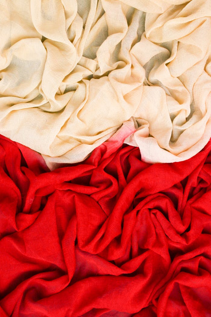 journey Vertical shot of vibrant red and beige draped fabrics creating a rich texture.